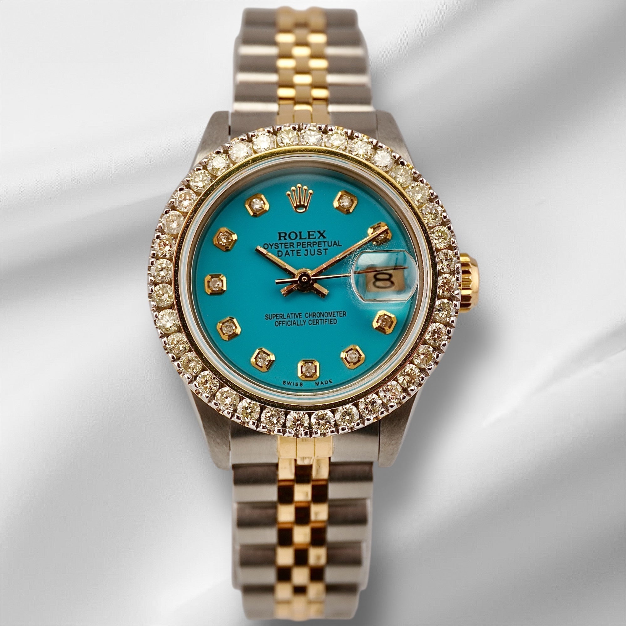 Rolex Ladies Datejust 26mm watch with ice-blue dial, 2ct diamond bezel, and two-tone 18k yellow gold and steel Jubilee bracelet on white satin.