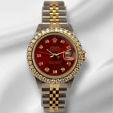 Rolex Ladies Datejust 26mm watch with red dial, 2ct diamond bezel, and two-tone 18k yellow gold and steel Jubilee bracelet on white satin background.